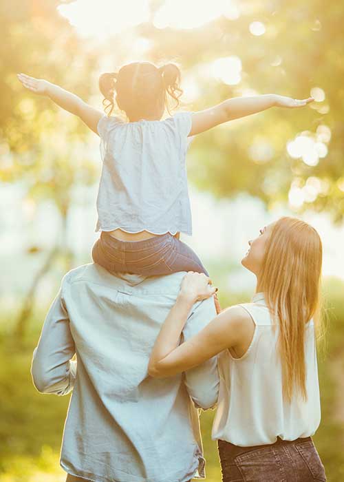 Une femme et son compagnon portant leur enfant sur les épaules